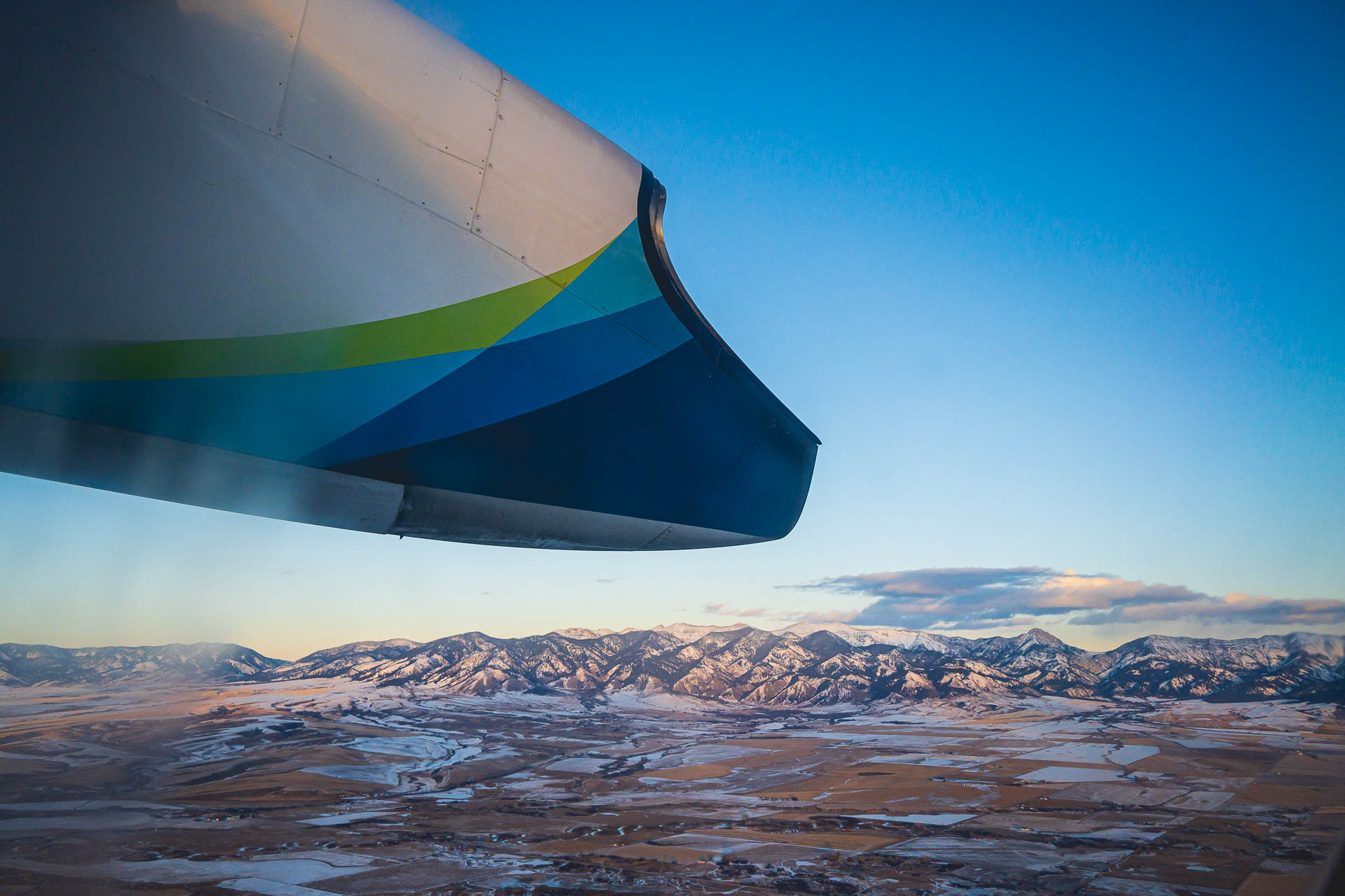 View of the Bridger Mountains taken from an airplane with the back side of the engine in frame on a blue sky day