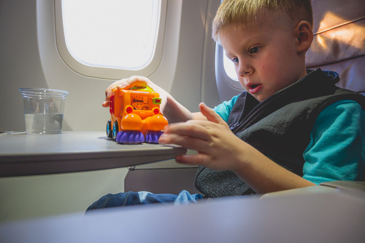 a boy playing with a toy on an airplane tray table