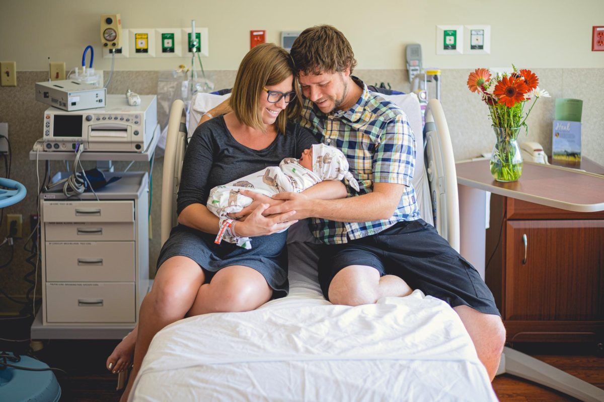 Parents look joyfully at their newborn baby in a hospital delivery room