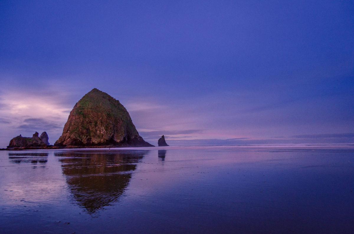 Haystack rock just past sunset reflecting in the ocean surf